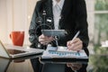 Businessman hand working at a tablet, computer and writing on a notepad with a pen in the office. on the wooden desk there a graph Royalty Free Stock Photo