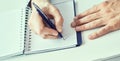 Businessman hand writing note on a notebook. Business man working at office desk. Close up of empty notebook on a Royalty Free Stock Photo