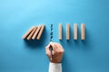 Businessman hand writing the word stop to prevent wooden dominos from collapsing Royalty Free Stock Photo