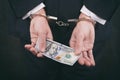 Businessman in handcuffs holding bribe hundred dollars Royalty Free Stock Photo