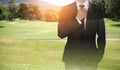 Businessman handles necktie showing confidence in golf course.