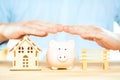 Businessman hands above a piggy bank, house model and a bench. Mortgage plan, insurance and residential tax saving strategy Royalty Free Stock Photo