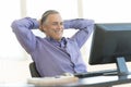 Businessman With Hands Behind Head Looking At Computer In Office Royalty Free Stock Photo