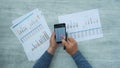 Businessman Hands Checking Reported Profits On Paper And Smartphone.