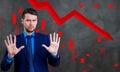 Businessman with palms shows refusal gesture over down red arrow. Royalty Free Stock Photo