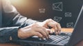 Businessman hands using Laptop typing on keyboard and surfing the internet on office table with email icon, email marketing Royalty Free Stock Photo