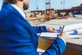 Businessman in hardhat and suit making notes on plans