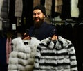 Businessman with hat and expensive overcoats. Customer with beard presents furry coats. Royalty Free Stock Photo