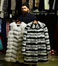 Businessman with hat and expensive overcoats. Customer with beard chooses furry coats. Royalty Free Stock Photo