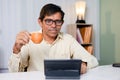 Businessman having coffee while using or reading news, social media and internet on digital tablet at office - concept Royalty Free Stock Photo