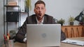 Businessman hiding behind laptop computer, making funny face, fooling around, putting his tongue out Royalty Free Stock Photo