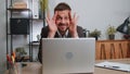 Businessman hiding behind laptop computer, making funny face, fooling around, putting his tongue out Royalty Free Stock Photo