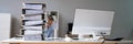 Businessman Hiding Behind The Stack Of Folders On Desk Royalty Free Stock Photo