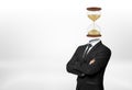 A businessman with his arms folded in front stands on white background and has his head replaced with a hourglass. Royalty Free Stock Photo