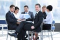 Businessman and his business team with financial documents sitting at a Desk in the lobby of the Bank. Royalty Free Stock Photo