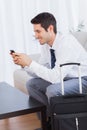 Businessman with his suitcase using mobile phone smiling Royalty Free Stock Photo