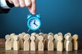 A businessman is holding an alarm clock over a crowd of people. Time management. Hourly wages, strict work limits and time Royalty Free Stock Photo