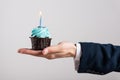 Businessman holding birthday cupcake with birning candle. Business greeting card. 1 year. Corporate party. Copy space