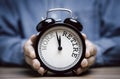 Businessman holding black alarm clock with clockwise countdown from work to retirement