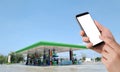 Businessman holding blank screen for text on smartphone, mobile, cell phone with blurry oil station Royalty Free Stock Photo