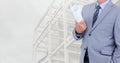 Businessman holding blueprints against construction site in background Royalty Free Stock Photo