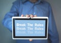 Businessman holding Break The Rules word on a tablet screen.