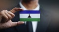 Businessman Holding Card of Lesotho Flag Royalty Free Stock Photo
