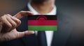 Businessman Holding Card of Malawi Flag Royalty Free Stock Photo