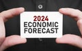 Businessman holding a card with text 2024 ECONOMIC FORECAST, business concept