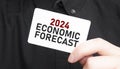 Businessman holding a card with text 2024 ECONOMIC FORECAST, business concept