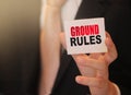 Businessman holding a card with text ground rules. Business concept