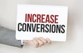 businessman holding a card with text INCREASE CONVERSIONS