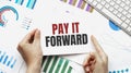 Businessman holding a card with text PAY IT FORWARD. Keyboard, diagram and white background Royalty Free Stock Photo