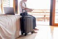 Businessman holding cellphone sitting on bed with suitcase in hotel room. Royalty Free Stock Photo