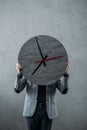 businessman hiding face behind round wall clock