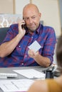 businessman holding color swatch while talking on mobile phone