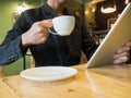 Businessman holding cup of coffee while read news on tablet