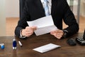 Businessman Holding Document At Desk