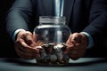Businessman holding glass jar with coins. Saving money for retirement concept. Businessman saving money in a glass jar, top