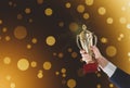 Businessman holding gold trophy cup on background, closeup. Space for text Royalty Free Stock Photo