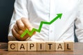 A businessman is holding a green up arrow above the word Capital. Increasing the attractiveness of the conditions for business Royalty Free Stock Photo