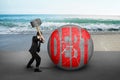 Businessman holding hammer hitting cracked DEBT ball with sea be