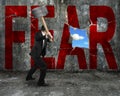 businessman holding hammer hitting red FEAR word on concrete wall