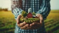 Businessman holding on his hands a farm with a barn, fields and silo tower. Running an agribusiness. Invest in food production.