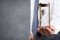 Businessman holding hourglass in his hand. Deadline and time management concept.