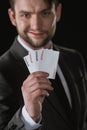 Businessman holding Joker cards in hand isolated on black