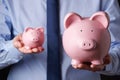 Businessman Holding Large And Small Piggy Bank Royalty Free Stock Photo