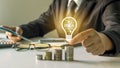 Businessman holding a light bulb, ideas on his desk, ideas for finance. Royalty Free Stock Photo