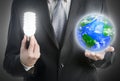 Businessman holding a light bulb and planet Earth