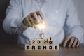 Businessman holding lightbulb on flipping 2020 to 2021 trends print screen on wooden block cubes. New idea business fashion Royalty Free Stock Photo